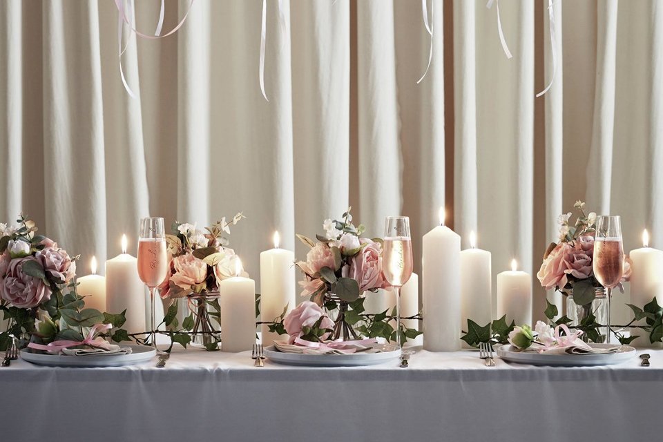 A dining table decorated for a wedding dinner with candles and flowers.